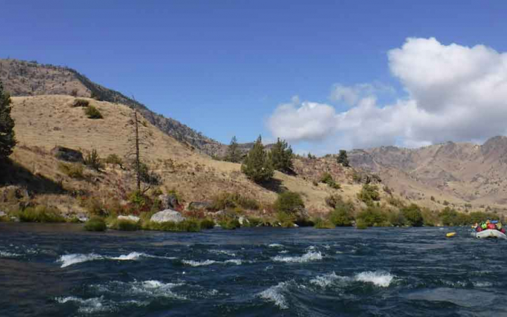 a raft navigates choppy waters with mountains in the background